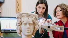 赌博娱乐平台网址大全 professor and her student examine an ancient sculpted bust.
